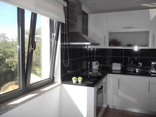 a kitchen with white cabinets and a large window at Quinta dos Carvalhais - Serra da Estrela in Fornos de Algodres