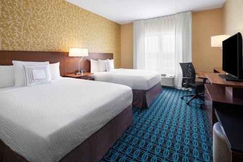 a hotel room with two beds and a desk and a television at Fairfield Inn & Suites by Marriott Poplar Bluff in Poplar Bluff