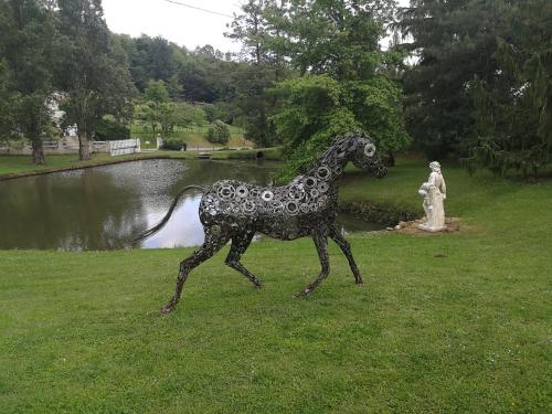 a statue of a horse in the grass next to a pond at le jardin d Eau in Lamothe-Montravel