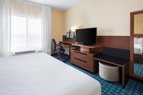 a hotel room with a bed and a desk with a television at Fairfield Inn & Suites by Marriott Poplar Bluff in Poplar Bluff
