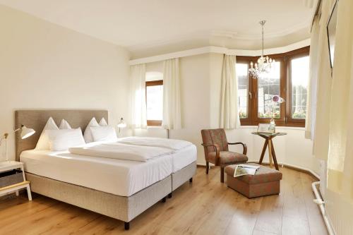 - une chambre avec un grand lit blanc et une chaise dans l'établissement Unterwirt - Das kleine Gourmethotel, à Ebbs
