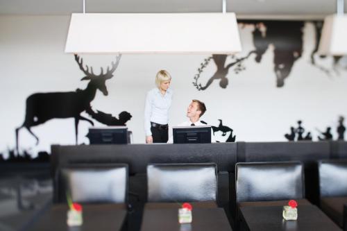 a woman standing behind a desk with a man at Mövenpick Hotel Stuttgart Airport in Stuttgart