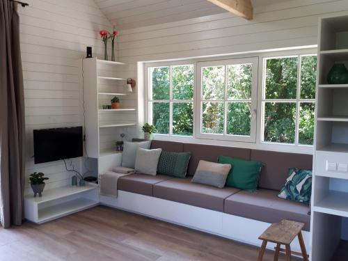 a living room with a couch and two windows at Lodges near the Rhine - Sustainable Residence in Hazerswoude-Rijndijk