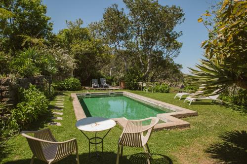 a backyard with a pool and two chairs and a table at Casa Da Muda in Ponta do Pargo