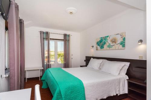 ein Schlafzimmer mit einem Bett mit einer grünen Decke in der Unterkunft Graca Hotel in Évora