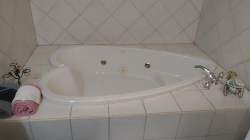a white bath tub in a white tiled bathroom at Midway Lodging in Cornish