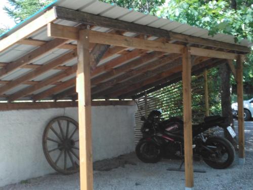 a motorcycle parked under a wooden pergola at NESTOR HOTEL GAP et Restaurant in Gap