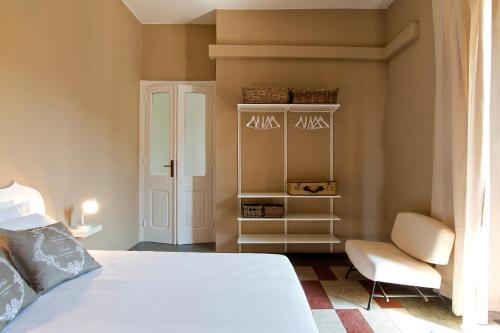 sypialnia z białym łóżkiem i krzesłem w obiekcie BluLassù City Center Rooms w Cagliari