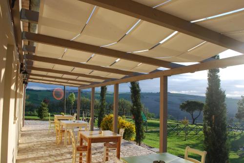 a pergola with tables and chairs on a patio at Le Maraclà Country House in Iesi
