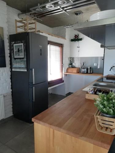 a kitchen with a refrigerator and a wooden counter top at Pensjonat Stary Spichlerz in Ełk
