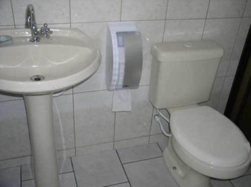 Łazienka z białą toaletą i umywalką w obiekcie Hotel Pousada Mineirinho w mieście Balneário Praia do Leste