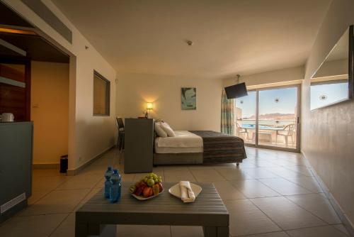 Neptune Eilat By Dan Hotels في إيلات: غرفة في الفندق بها سرير وطاولة مع وعاء من الفواكه