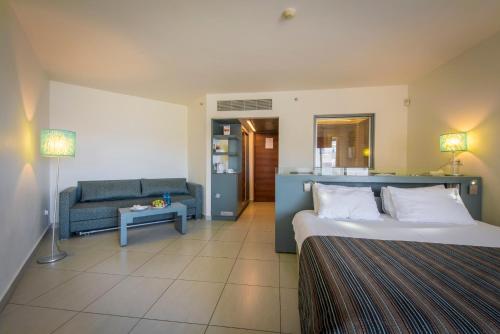 a hotel room with a bed and a couch at Neptune Eilat By Dan Hotels in Eilat