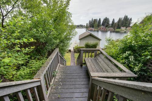 a wooden staircase leading down to a lake with a bench at Delake House in Otis