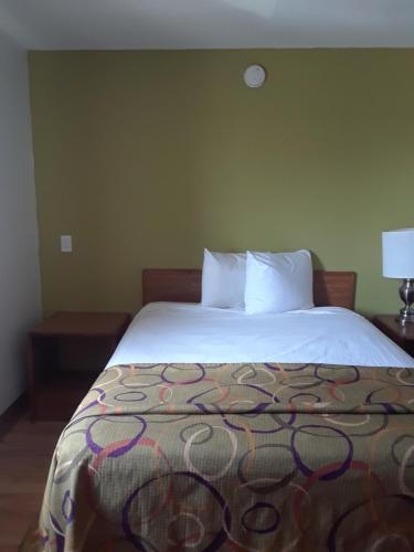 a bedroom with a large bed with a white bedspread at Welcome Suites Hazelwood Extended Stay Hotel in Hazelwood