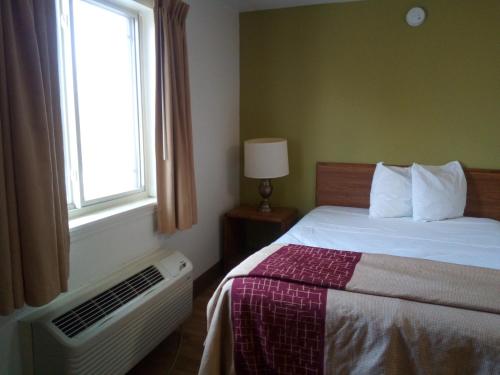 a bedroom with a bed with a window and a radiator at Welcome Suites Hazelwood Extended Stay Hotel in Hazelwood