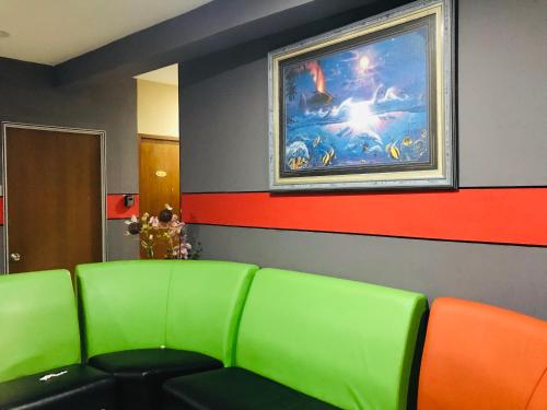 a waiting room with green chairs and a painting on the wall at Home Inn Hotel in Ipoh