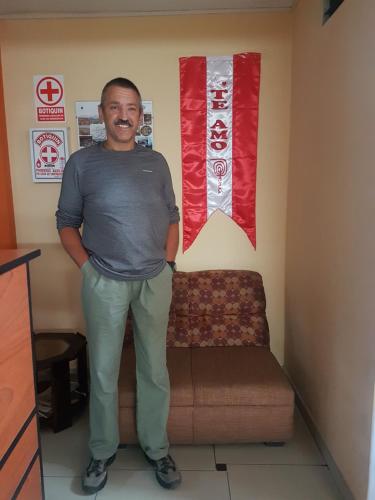 a man standing in a room with a couch at Hostal Los Pinos in Huancayo