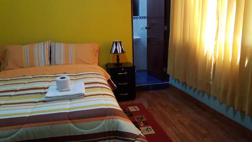 a bedroom with a bed with a lamp and a window at Hostal Los Pinos in Huancayo