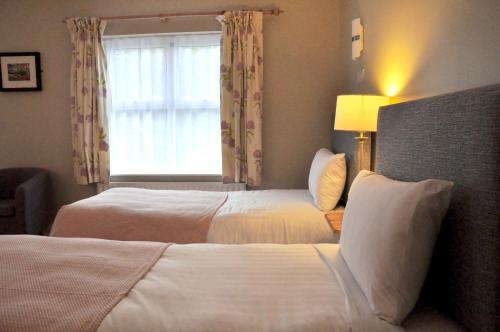 a hotel room with two beds and a window at Killilagh Accommodation in Doolin