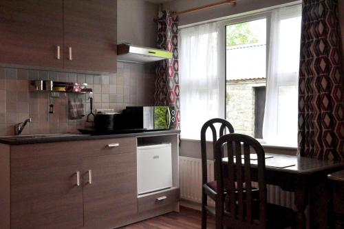 a kitchen with wooden cabinets and a table and chairs at Killilagh Accommodation in Doolin