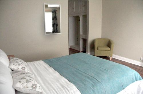 a bedroom with a bed with a chair and a mirror at Killilagh Accommodation in Doolin