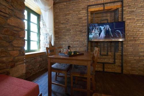 a dining room with a table and a tv on a brick wall at Athenian Residences in Athens