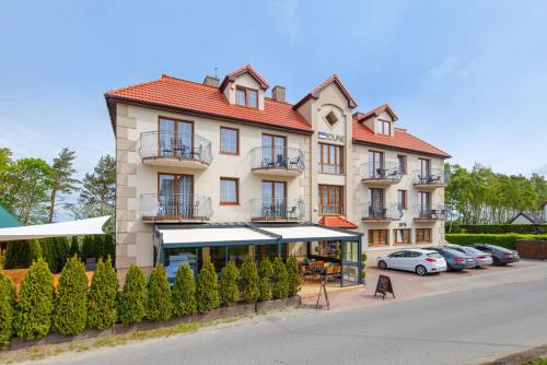 un grand bâtiment avec des voitures garées sur un parking dans l'établissement Villa Dune, à Sarbinowo
