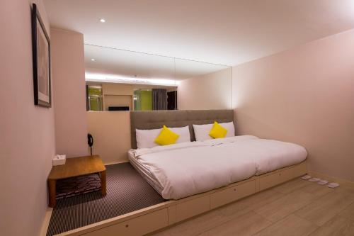 a bedroom with a large white bed with yellow pillows at Crystal Inn Sun Moon Lake in Yuchi