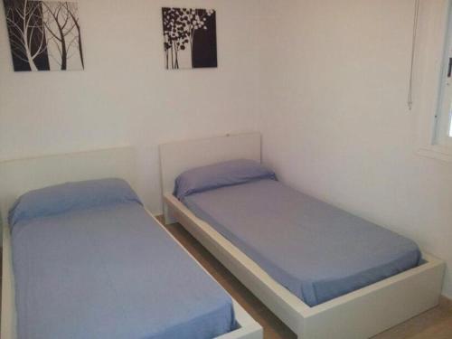 dwa łóżka w pokoju z niebieską pościelą w obiekcie apto Fradera w mieście La Savina