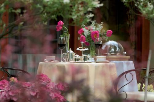 a table with two glasses of wine and flowers on it at Grotthuss Boutique Hotel Vilnius in Vilnius
