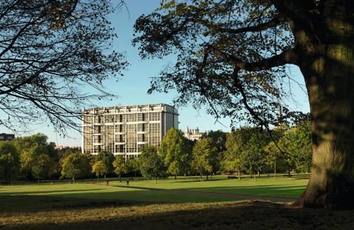 a large building in a park with a tree at Royal Garden Hotel in London