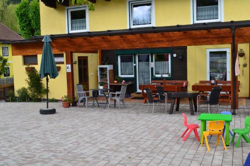 a patio with chairs and tables and an umbrella at Pension Haus Rohrmoser in Annaberg im Lammertal