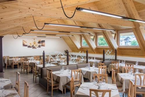 comedor con mesas y sillas blancas y techos de madera en Hotel Milano, en Tione di Trento