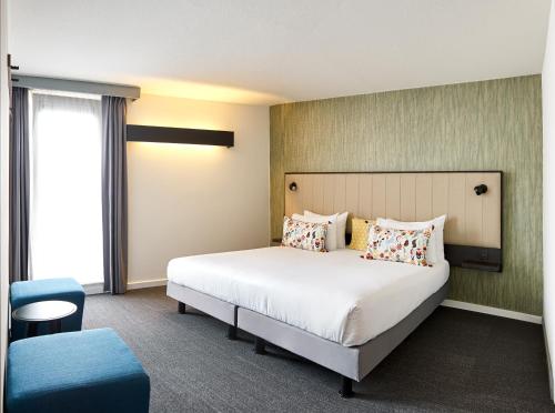a bedroom with a large bed and a blue chair at Best Western Hotel Wavre in Wavre