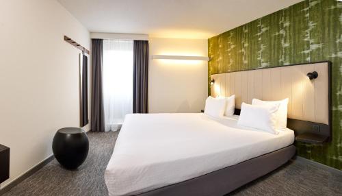 a hotel room with a large bed and a green wall at Best Western Hotel Wavre in Wavre