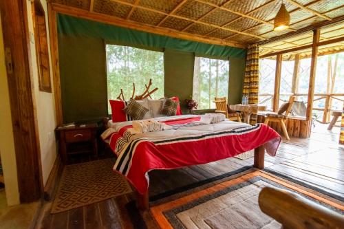 a bedroom with a bed in a room with a large window at Rushaga Gorilla Lodge in Bugambira