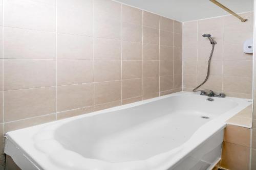a white bath tub in a bathroom with tiles at Flexistay Tulsi Aparthotel in Croydon