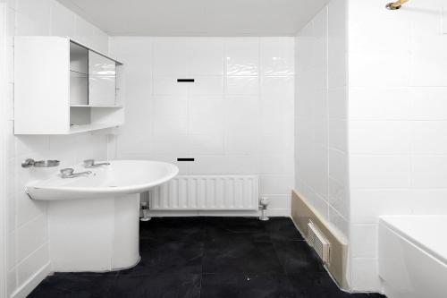 ein weißes Badezimmer mit einem Waschbecken und einer Badewanne in der Unterkunft Flexistay Tulsi Aparthotel in Croydon