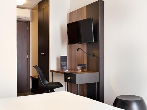 a hotel room with a desk and a tv on a wall at Best Western Hotel Wavre in Wavre