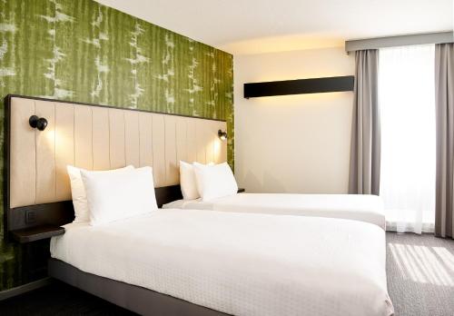 two beds in a hotel room with green wallpaper at Best Western Hotel Wavre in Wavre