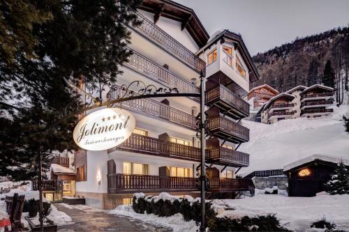 a large building with a sign in the snow at Jolimont Apartments in Zermatt