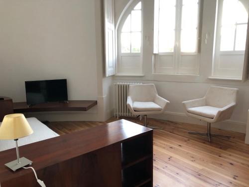 a living room with two chairs and a desk and a tv at Rua Tenente Campos Rego, Ground Floor in Coimbra