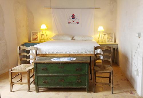 a bedroom with a bed with a green dresser and two chairs at BORGO PETELIA, Casa Chiarotti, Antica casa con scala esterna in Strongoli