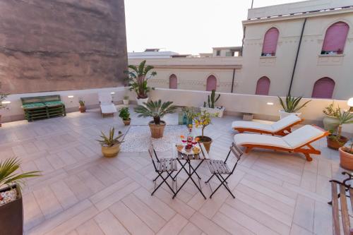 a rooftop patio with chairs and tables and potted plants at B&B Kalavrìa in Reggio Calabria