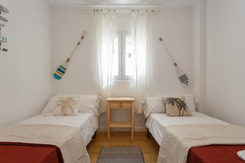 Habitación con 2 camas y mesa. en BARQUILLAS de la Caleta Home by Cadiz4Rentals en Cádiz
