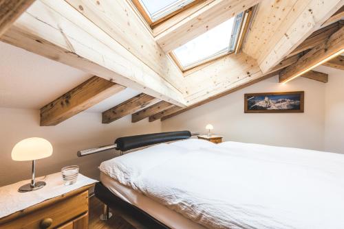 a bedroom with a white bed and wooden ceilings at Jolimont Apartments in Zermatt