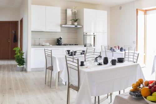 a kitchen with white tables and chairs in a room at B&B Alba sul Mare in Massignano