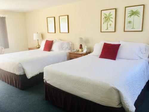 two beds in a hotel room with white and red pillows at Sesuit Harbor House in East Dennis