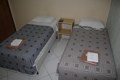 two beds in a hotel room with a tray on it at Hotel Reimann in Indaiatuba